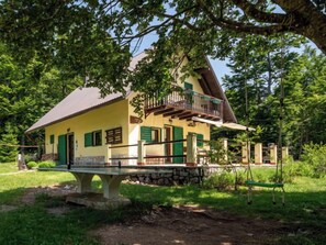 Uma casa de dois andares com varanda, cercada por vegetação exuberante.