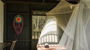 A room with a bed covered by a mosquito net, a ceiling fan, and a dreamcatcher on the wall. - Harrera Perhentian Long Beach (Pulau Perhentian Kecil)