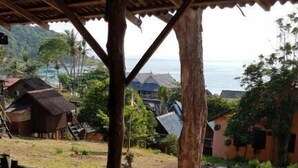 A wooden bench under a thatched roof, overlooking a coastal village with houses and a view of the sea. - Harrera Perhentian Long Beach (Pulau Perhentian Kecil)