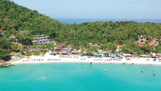 A coastal area with a beach, boats, and buildings. - Harrera Perhentian Long Beach (Pulau Perhentian Kecil)