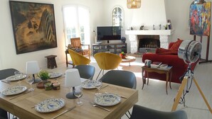 Un comedor con una mesa de madera preparada para cuatro personas, un sofá rojo y una chimenea.