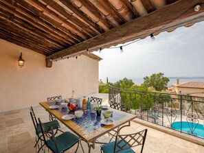 A dining area with a table set for four, outdoor seating, a pool, and a view of the sea. - Les Gaulois by Interhome (Les Issambres)