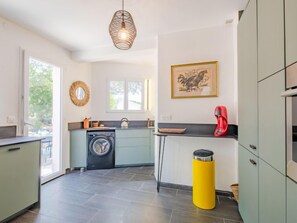 A compact kitchen with a washing machine, a sink, and a red coffee maker. - Les Gaulois by Interhome (Les Issambres)