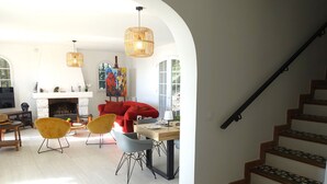 Amplia sala de estar con chimenea, comedor y escalera.