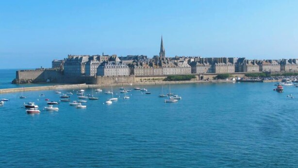 Un pueblo costero con un castillo fortificado y un puerto lleno de barcos.