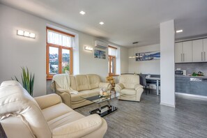A modern living room with leather sofas, a glass coffee table, and a view of the city through large windows. - Villa Roma Portorose - 3 Balcony (Piran)