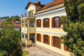 Un immeuble de deux étages doté d’un balcon, d’un escalier en pierre et offrant une vue sur les environs.