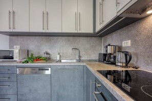 A modern kitchen with a dishwasher, microwave, coffee maker, and a granite countertop.