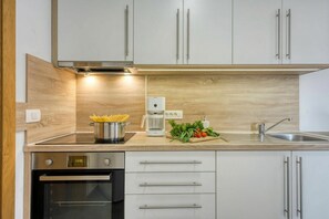 A modern kitchen with stainless steel appliances, wooden cabinetry, and a built-in oven.