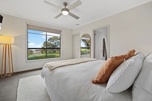 A bedroom with a bed, a ceiling fan, a window with a view, and a door. - Valley View Home | Sauna, Fire Pit, Pizza Oven (Port Lincoln)