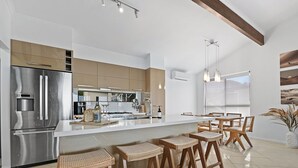 Eine moderne Küche mit einem Edelstahlkühlschrank, Holzbarhocker und einer großen Kochinsel.