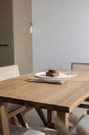 A wooden dining table with a woven placemat and stacked coasters. - Valley View Home | Sauna, Fire Pit, Pizza Oven (Port Lincoln)