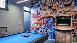 Relax and play in this vibrant space featuring a pool table and arcade machine.