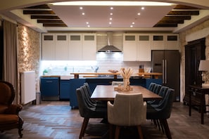 A modern kitchen with white cabinets, a central island, and a dining area with a wooden table and chairs.