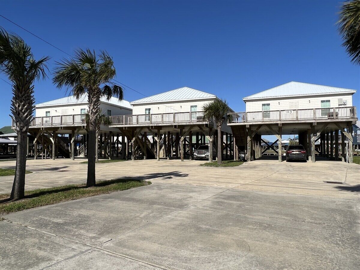 A waterfront building with a covered walkway and a parking area.
