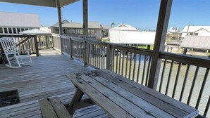 A wooden deck with picnic tables and a railing overlooking a body of water. - Point Fourchon Unit D (Golden Meadow)