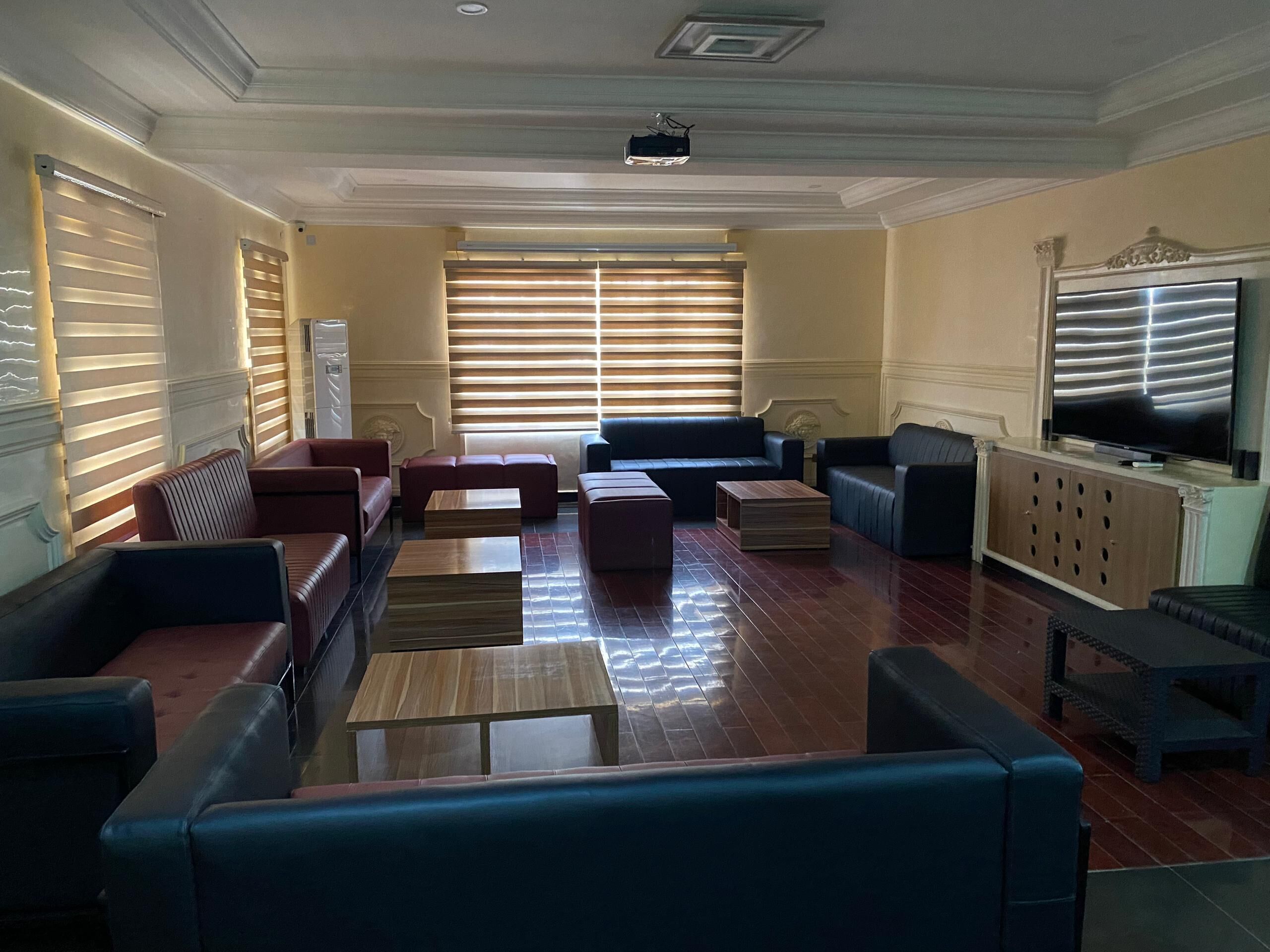 A spacious living room with a large flat-screen TV, leather sofas, and a wooden coffee table.