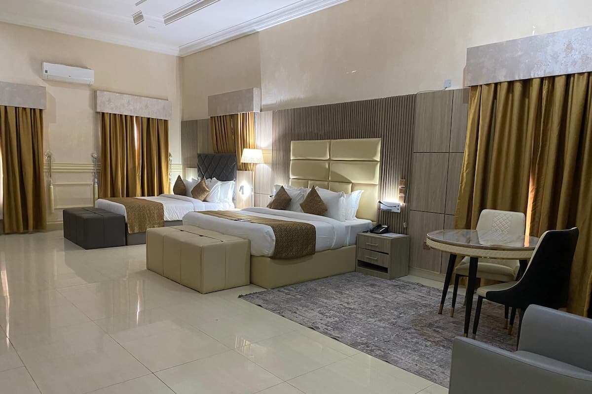 A hotel room with two beds, a desk, a chair, and a small table.