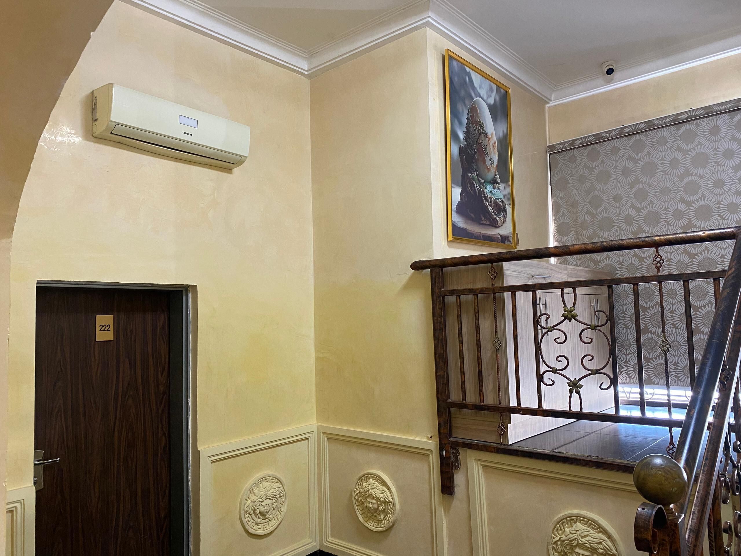 A staircase with ornate metal railings and a wooden handrail, leading to a landing with a door marked '222'.