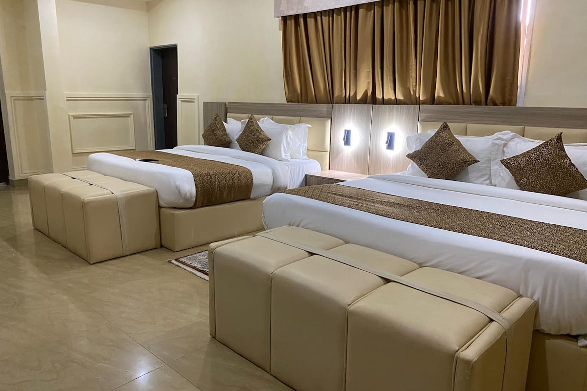 A hotel room with two beds, a large window with curtains, and a door.