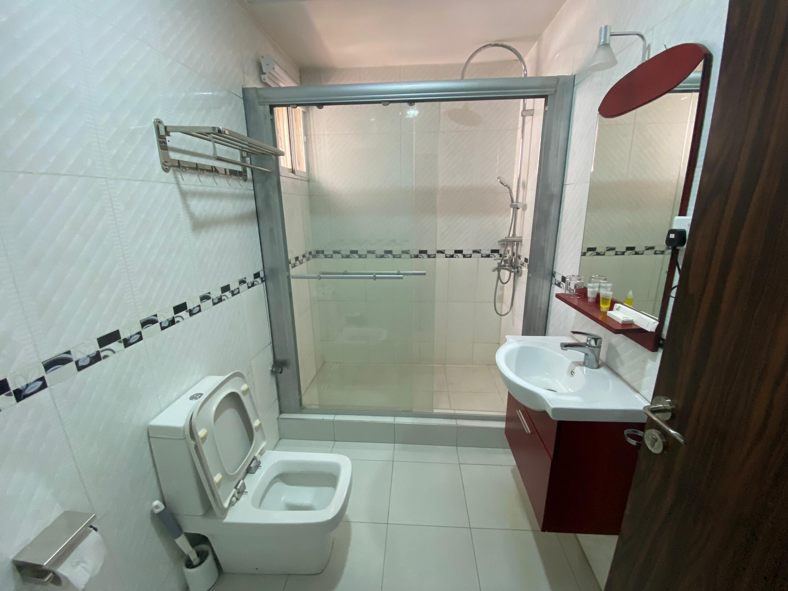 Un baño con ducha compartimentada con vidrio, inodoro, lavabo y espejo.