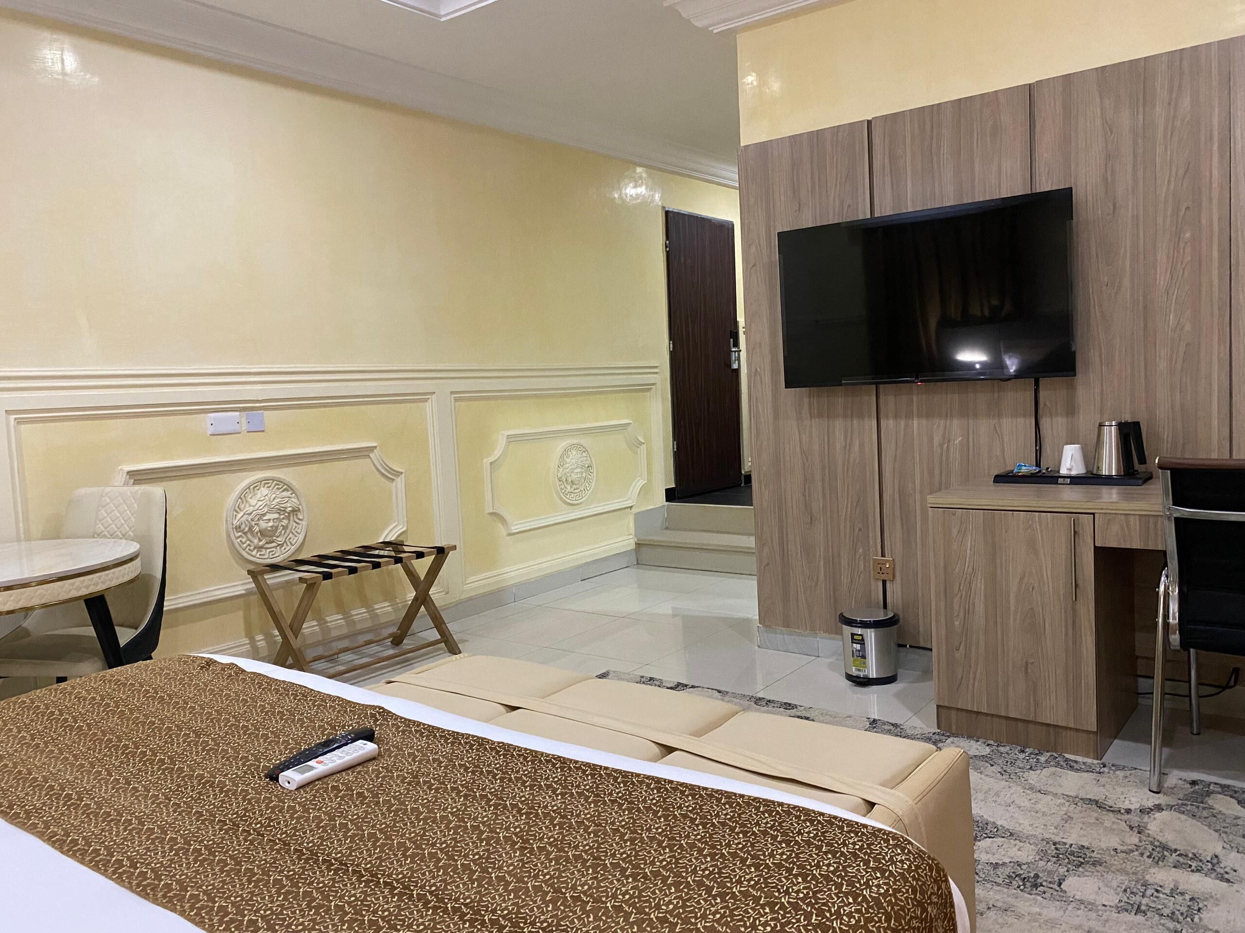 Ein Hotelzimmer mit Bett, Wandfernseher, kleinem Tisch mit Wasserkocher und Stuhl.
