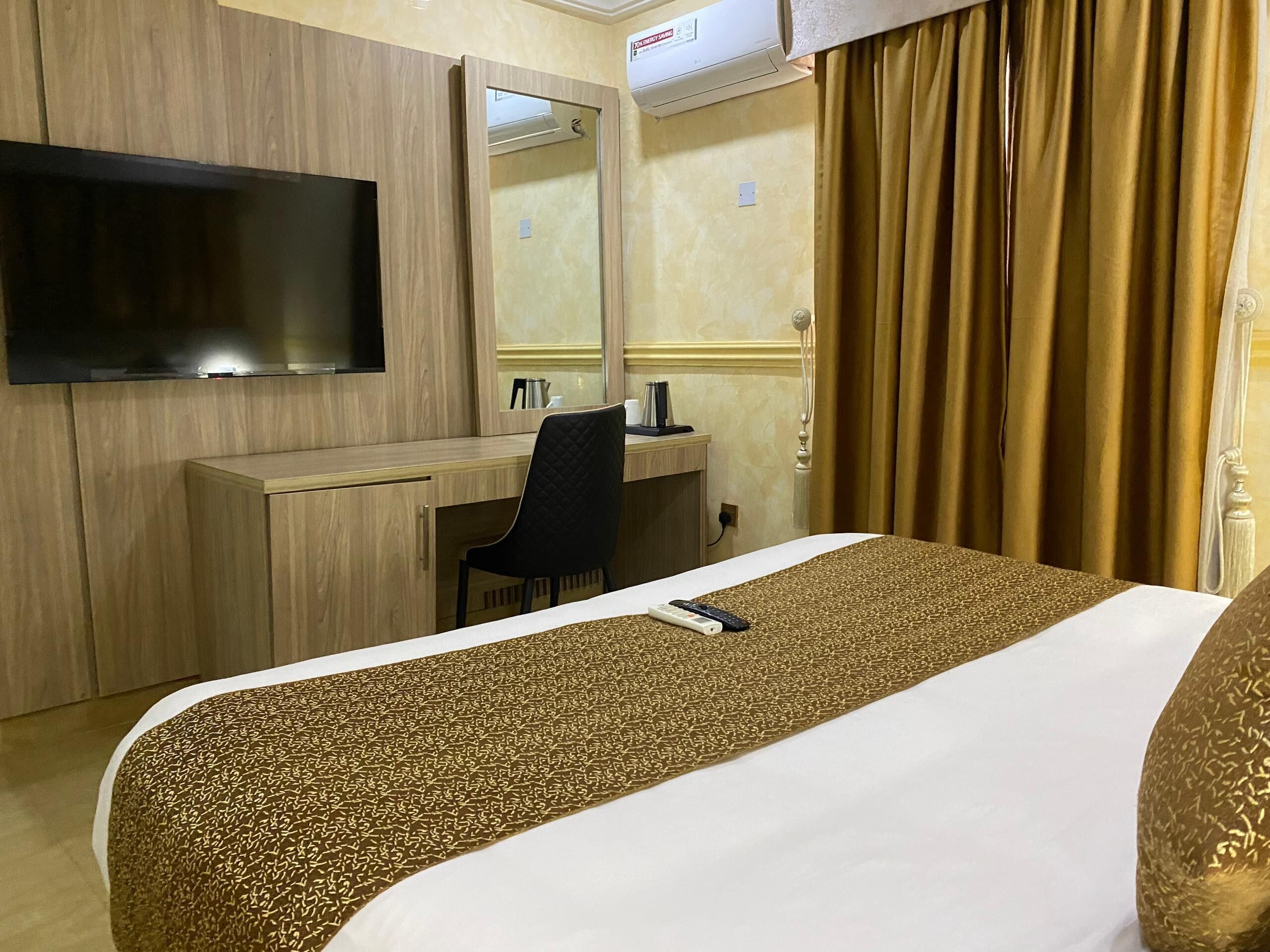 A hotel room with a bed, a desk, a chair, a television, and a window with curtains.
