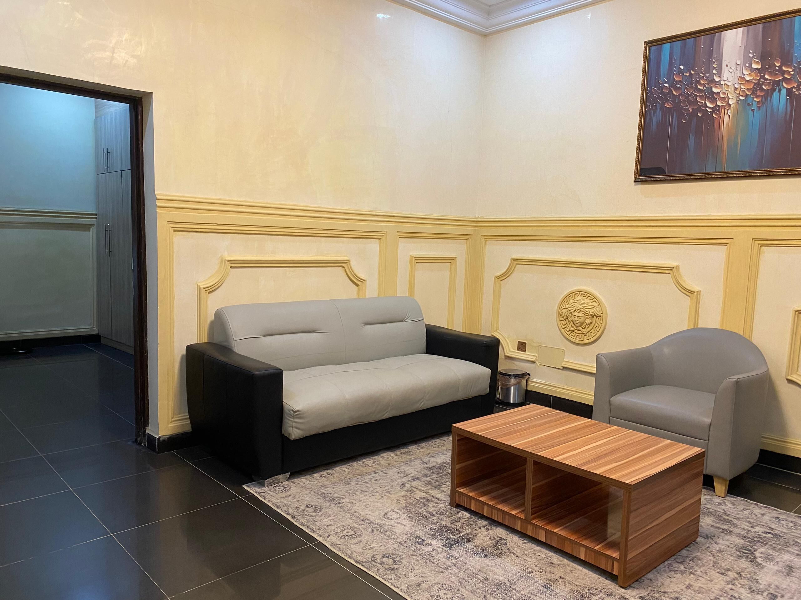Una habitación con un sofá gris, un sillón negro y una mesa de centro de madera.