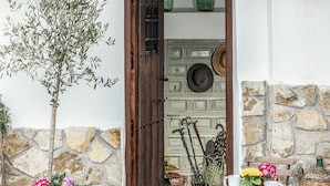 A rustic entrance with a wooden door, stone wall, and a potted tree. - MAJADA DEL CONDE (La Guardia)