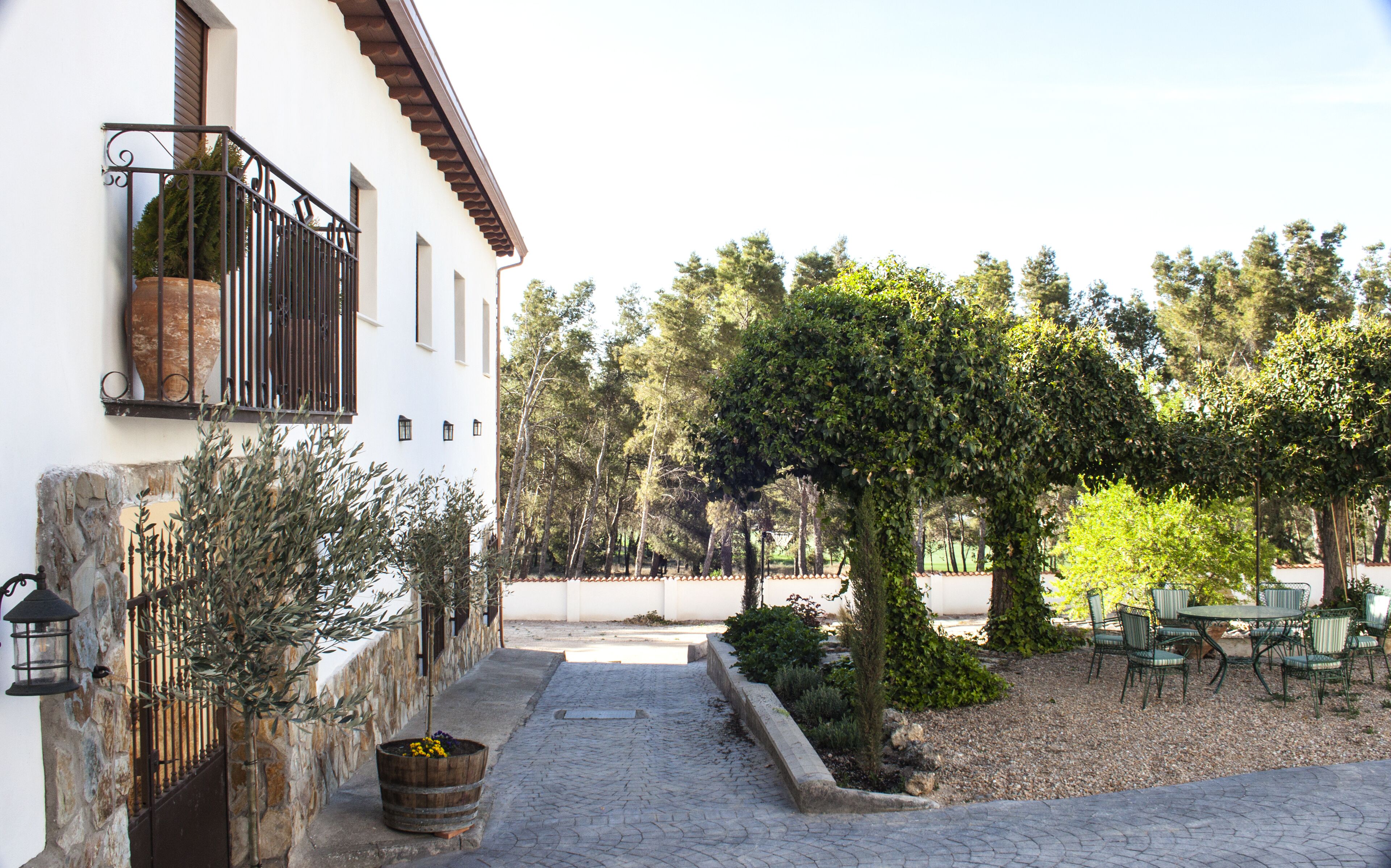 Un patio con sendero de piedra, mobiliario exterior y un edificio blanco con balcón.