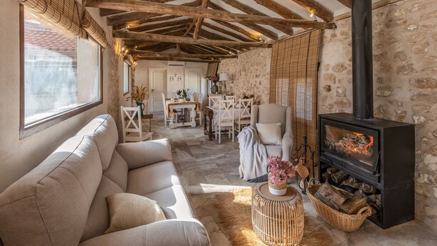 A cozy living room with a sofa, a fireplace, and a stone wall. - MAJADA DEL CONDE (La Guardia)