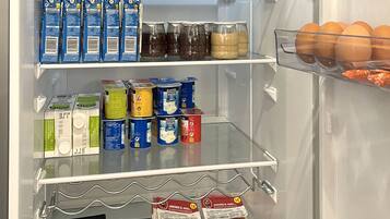 Un refrigerador lleno de diferentes alimentos, entre ellos leche, yogur y agua embotellada.