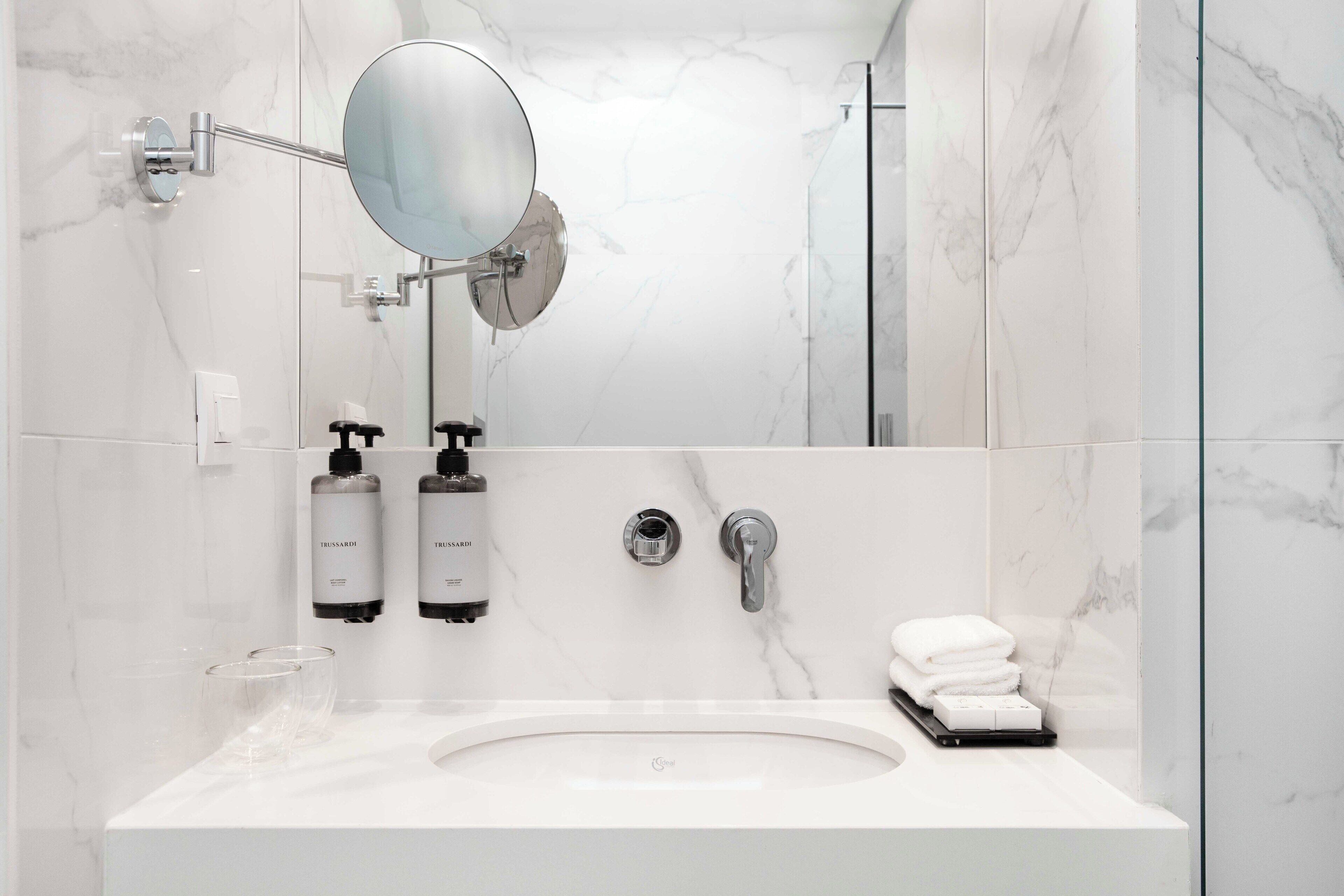 Une salle de bain moderne avec un lavabo blanc, un miroir et deux flacons de produits de toilette.