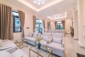 A modern living room with a sofa set, a glass coffee table, and a vase with flowers. - Sunset Hill Hotel (Lam Vien - Da Lat)