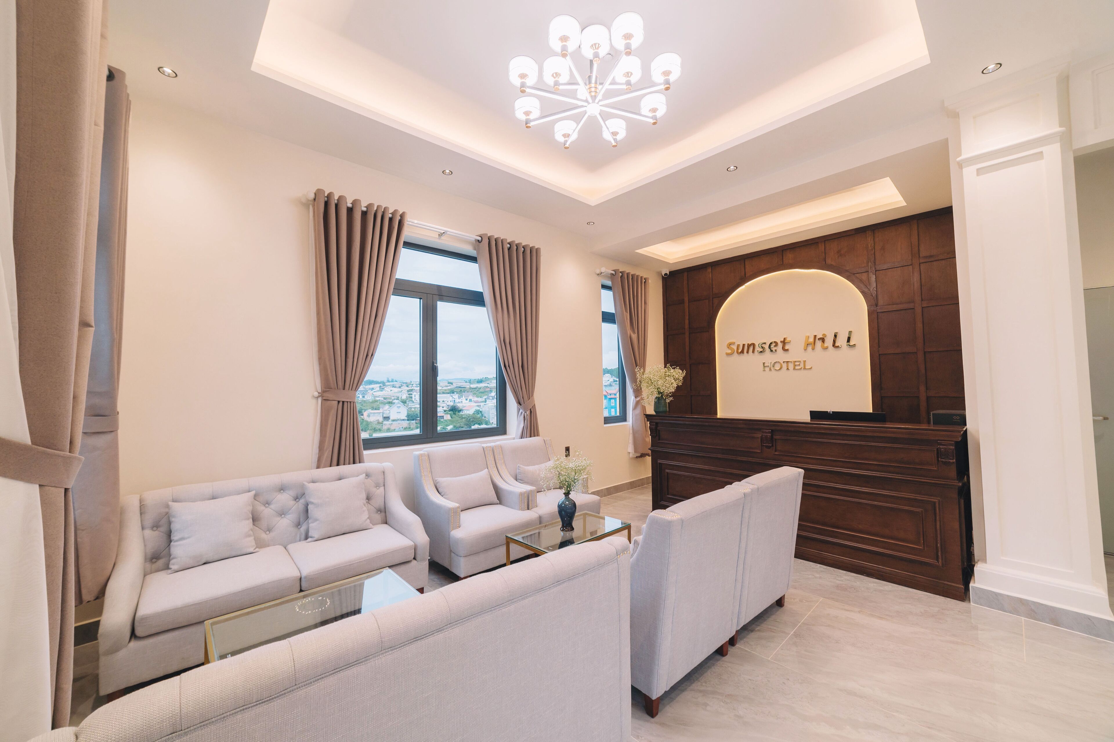 Un hall d’hôtel moderne avec un ensemble de canapés, un comptoir d’accueil et un lustre.