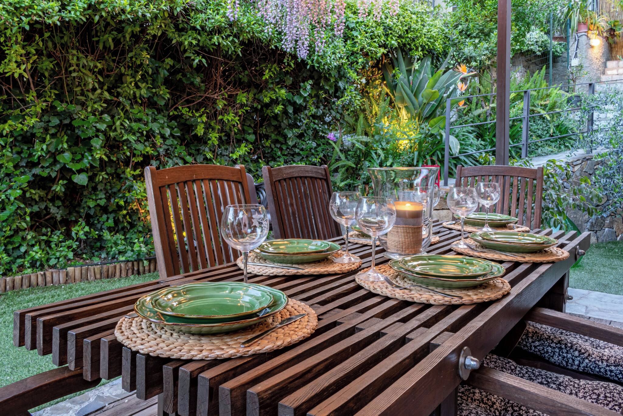A wooden dining table set with green plates, wine glasses, and a candle.