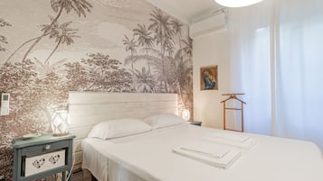 Une chambre à coucher comprenant un lit, une table de chevet, une lampe, un climatiseur fixé au mur et un tableau.