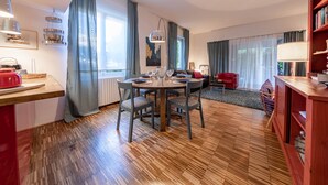 A modern living room with a round dining table, a red sofa, and a wooden floor.