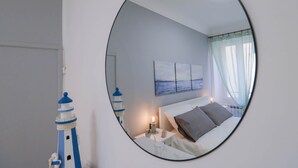 A bedroom with a bed, a nightstand, a lamp, a painting, and a lighthouse decoration.