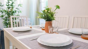 A dining table set with plates, glasses, and a vase of flowers.