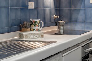 A kitchen with a white countertop, a coffee maker, a tea box, and a blue tiled backsplash. - SANREMO VISTA MARE - Elegante (Sanremo)