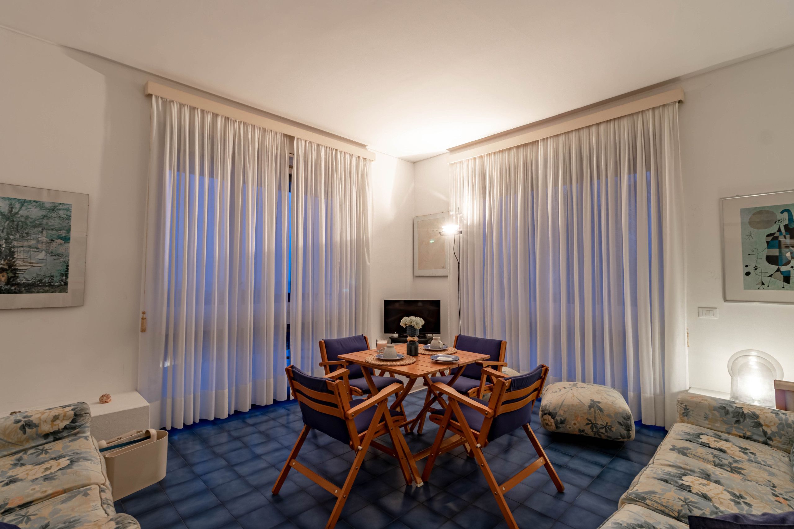 Een hotelkamer met een eettafel, stoelen, een bank en gordijnen.