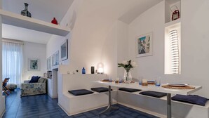 A modern living room with a sofa, a dining table with chairs, and a kitchen area.