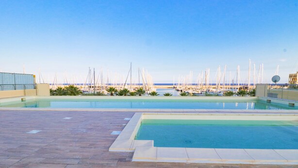 A rooftop swimming pool with a view of a marina and boats.