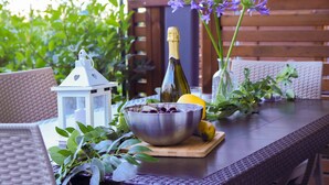 A table with a bottle of wine, a bowl of cherries, a lantern, and a vase with flowers.