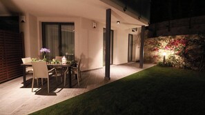 Une terrasse extérieure avec une table et des chaises, entourée d’un mur de pierre orné de plantes à fleurs.