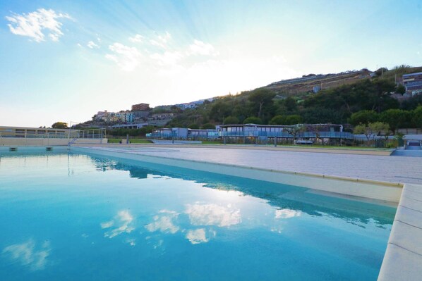 A swimming pool with a clear view of the surrounding buildings and a hilly landscape.