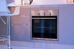 A modern kitchen with a built-in oven and a bar stool.