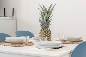 A dining table set with plates, bowls, glasses, and a pineapple centerpiece.