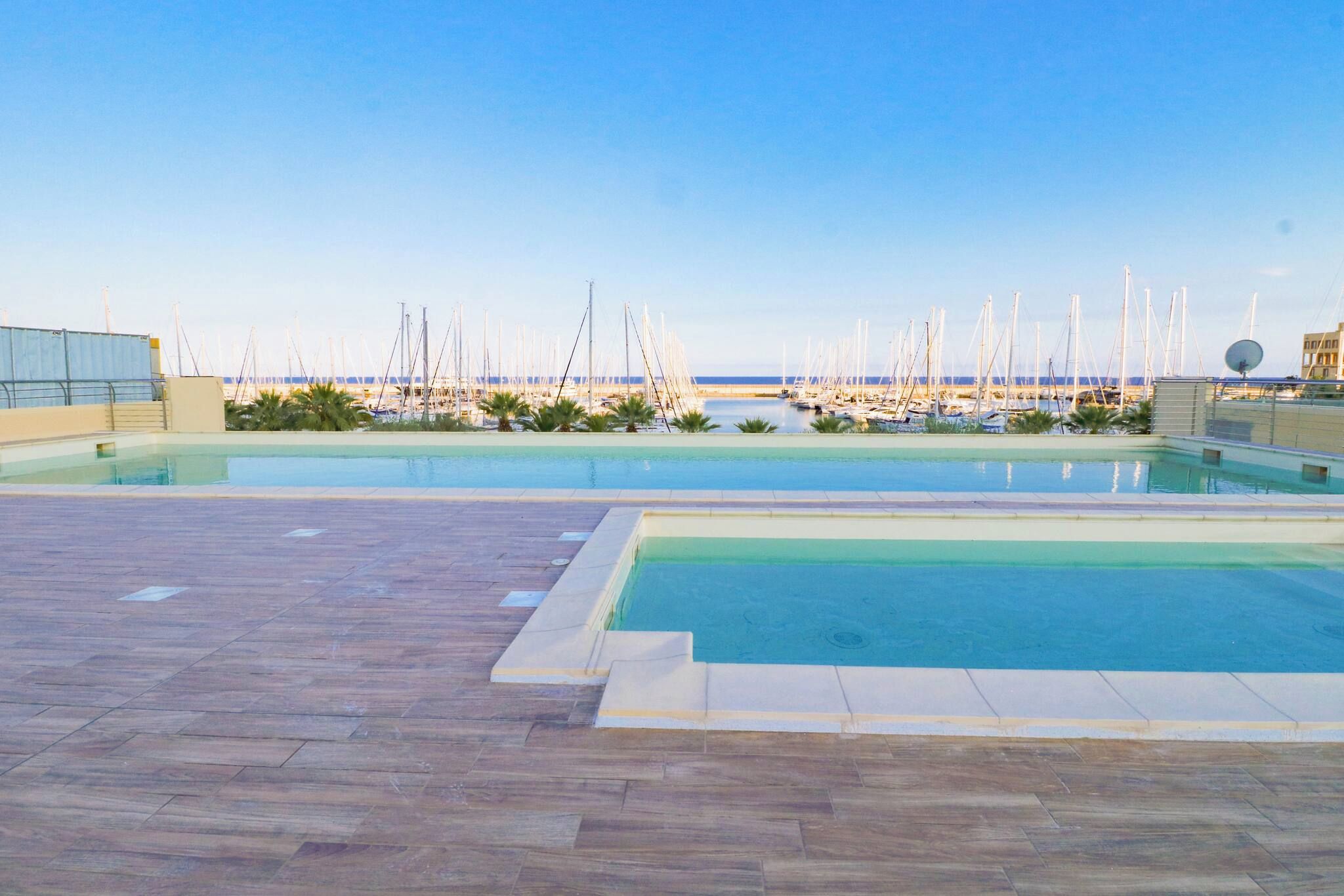 A rooftop pool area with clear views of a marina and boats.